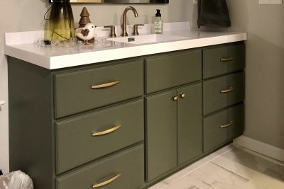 Green vanity with gold handles, white top, and undermount sink