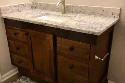 Rustic wooden vanity with granite top and undermount sink.