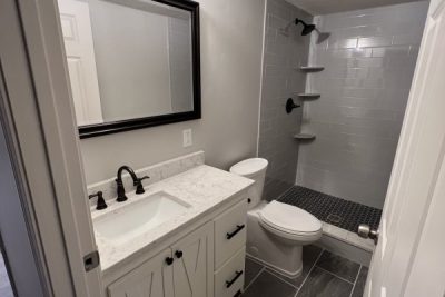 White bathroom with gray floor, white vanity, and walk-in shower