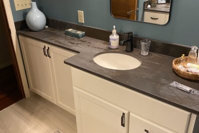Minimalist bathroom with cream vanity, round mirror, and teal wall