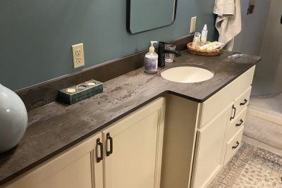 Minimalist bathroom with cream vanity, round mirror, and teal wall