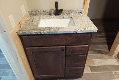 Compact dark wooden vanity with granite top and white sink
