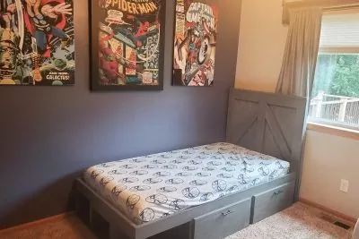 Bedroom with a gray-colored single bed and superhero wall art
