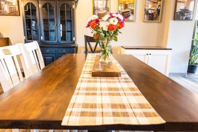 Dining table with flowers, plaid runner, and hutch