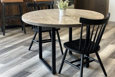 Round wood-top table with black chairs in a bright room