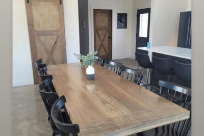 A spacious dining room featuring a large wooden table, black chairs, and a rustic sliding barn door