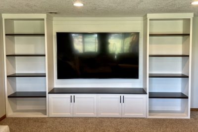 White built-in shelving unit around a TV with dark wood countertop