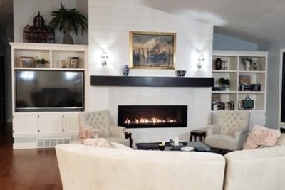 Elegant living room with a fireplace, mounted TV, and decorative shelving.