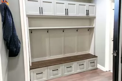 White mudroom bench with cabinets on top and bottom 