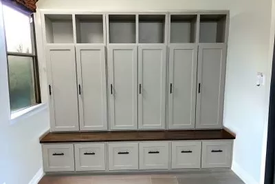 Gray hall tree with cabinets in middle and bottom sections and wooden texture shelf