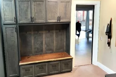 Charcoal stained mudroom bench with wooden shelf in a bright room 